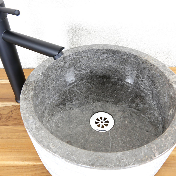 Round stone washbasin with a finely ground surface, detailed view of the basin interior and drain.