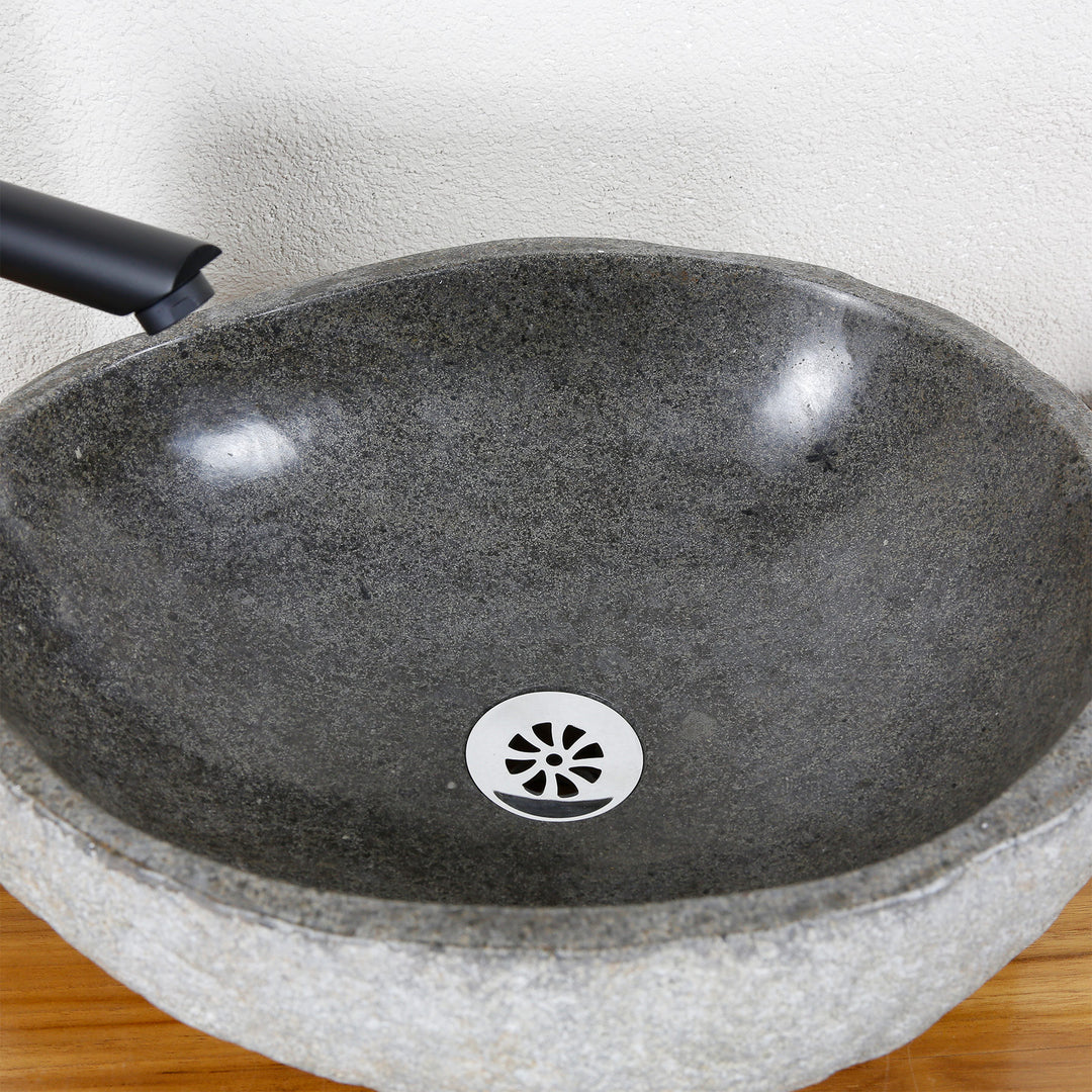 Detailed view of an oval stone sink made of river stone with a finely polished inner surface and a central drain valve