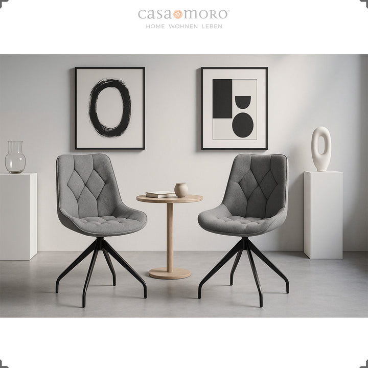 Two gray dining room chairs with 360° swivel function and black metal frame - modern seating area with side table and minimalist wall decoration