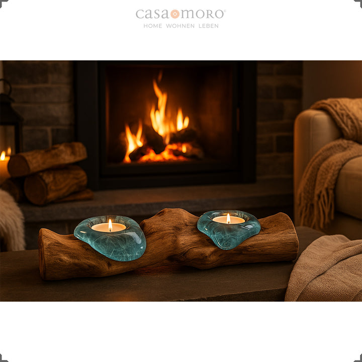 Tea light holder made of glass and burl wood in front of a fireplace, its soft light enhances the cozy living atmosphere.