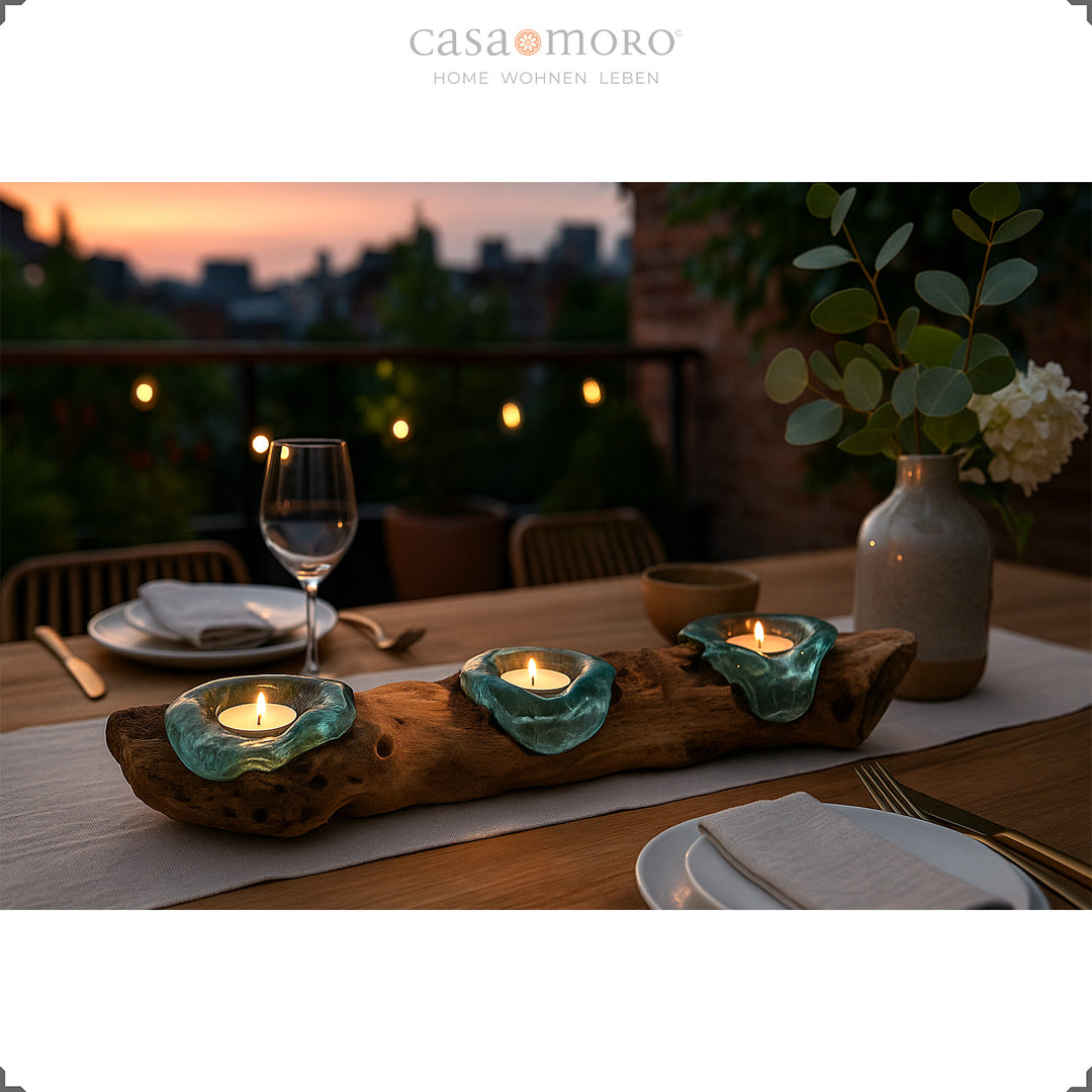 Three-part tea light holder made of glass and root wood as a table decoration on a terrace at sunset, atmospheric dinner