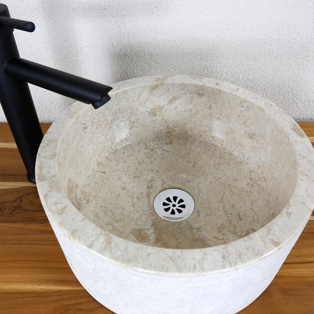 Detailed view of a round countertop washbasin in a light marble look with a smooth inner surface and a fine drain.