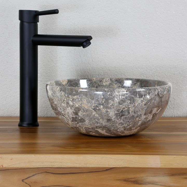 Round natural stone countertop washbasin with grey-brown grain on a wooden top, combined with a black stand-alone tap