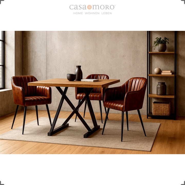Three antique brown leather armchairs with vertical quilting at a wooden table with a black metal frame in a modern dining room with warm lighting and minimalist decoration.