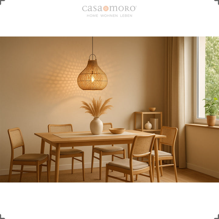 Rattan lamp above dining table in natural dining room with warm light and harmonious furnishings