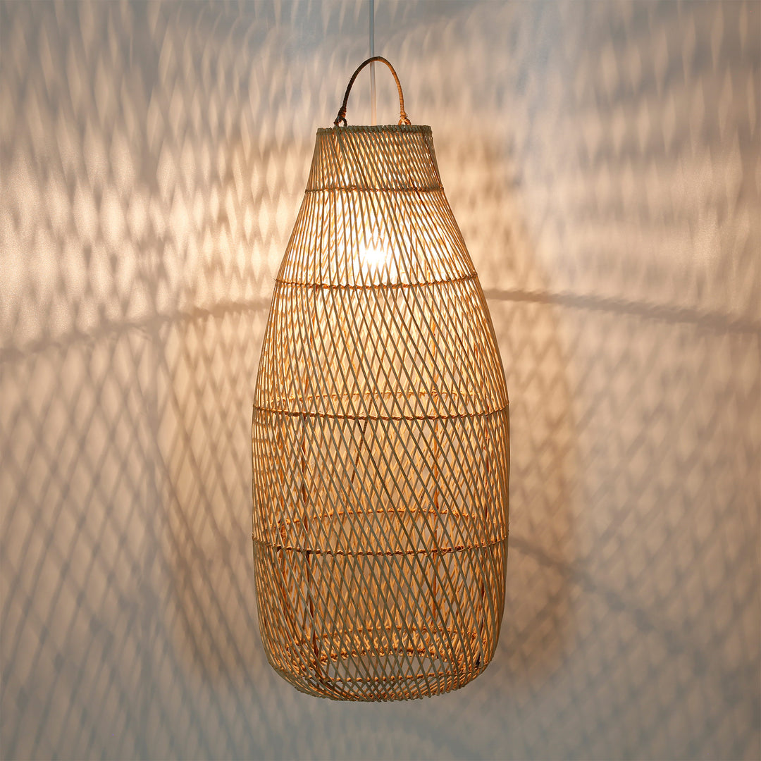 Tall rattan lamp with a fine weave pattern and a warm play of light on the wall