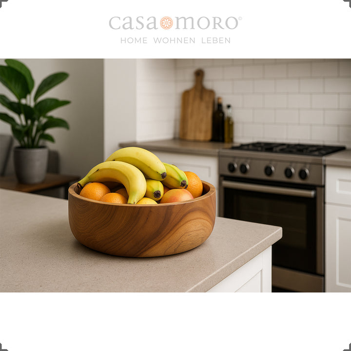 Teak bowl with bananas and citrus fruits on kitchen island