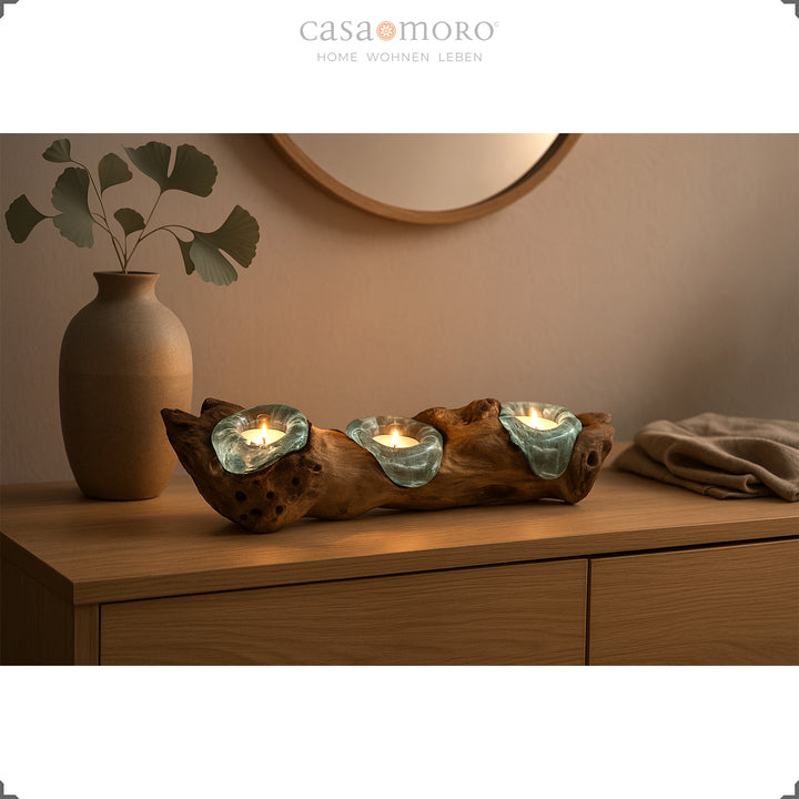Three-piece tea light holder made of glass and burl wood on a wooden chest of drawers, warm light in the modern living room