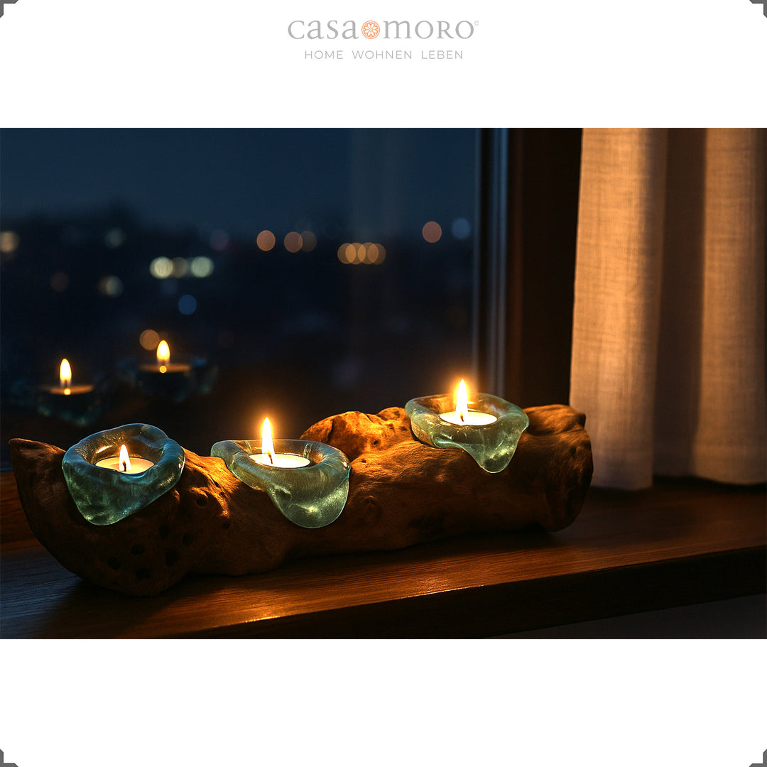 Elongated 3-seater tealight holder made of glass and root wood on a windowsill, its warm light glows gently into the nighttime atmosphere