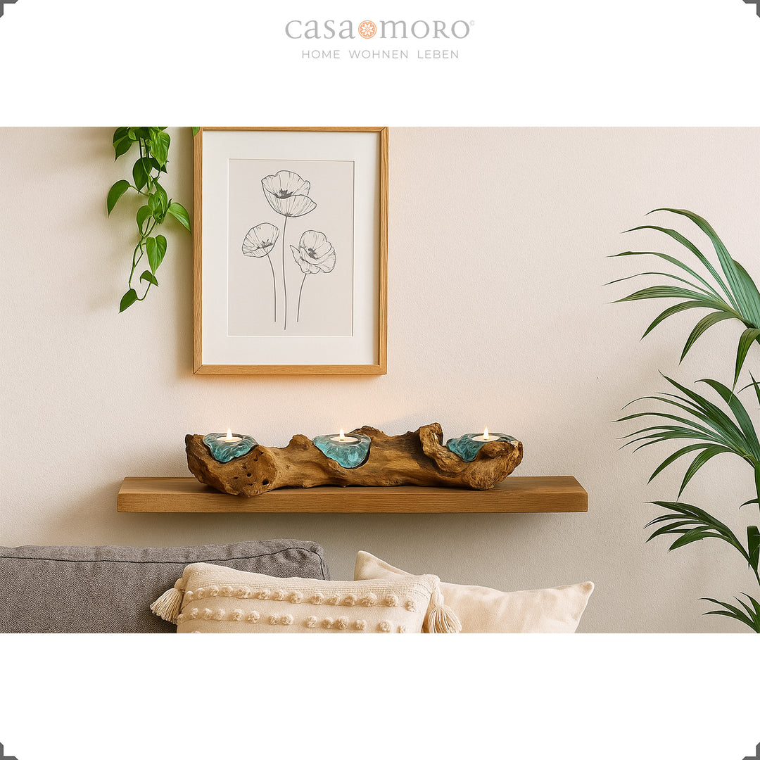 Three tea light holders made of glass and burl wood on a wall shelf, decorated in a warm living room ambience