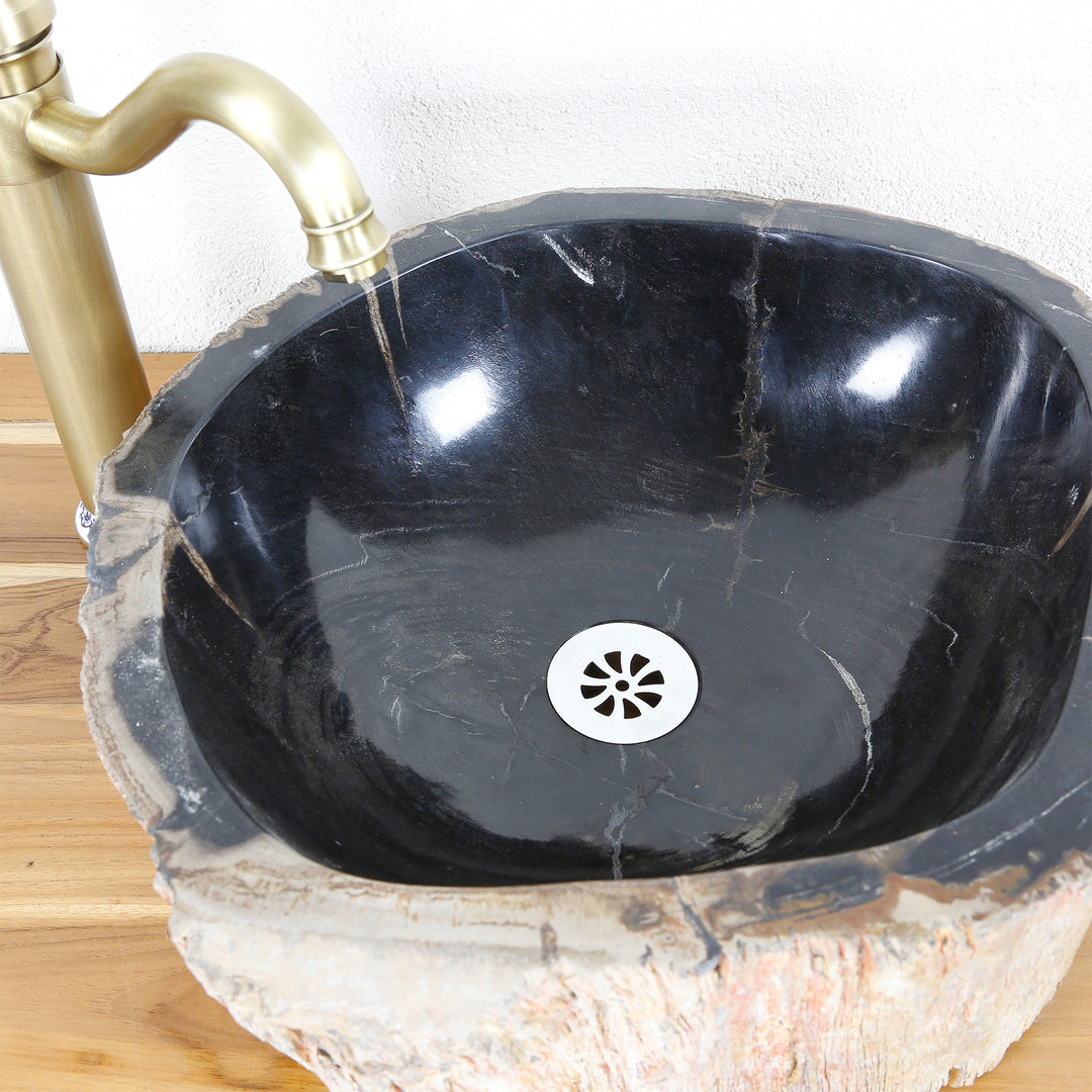 Stone sink made of petrified wood with dark polished interior surface, top view with drain and brass fitting on wooden top.