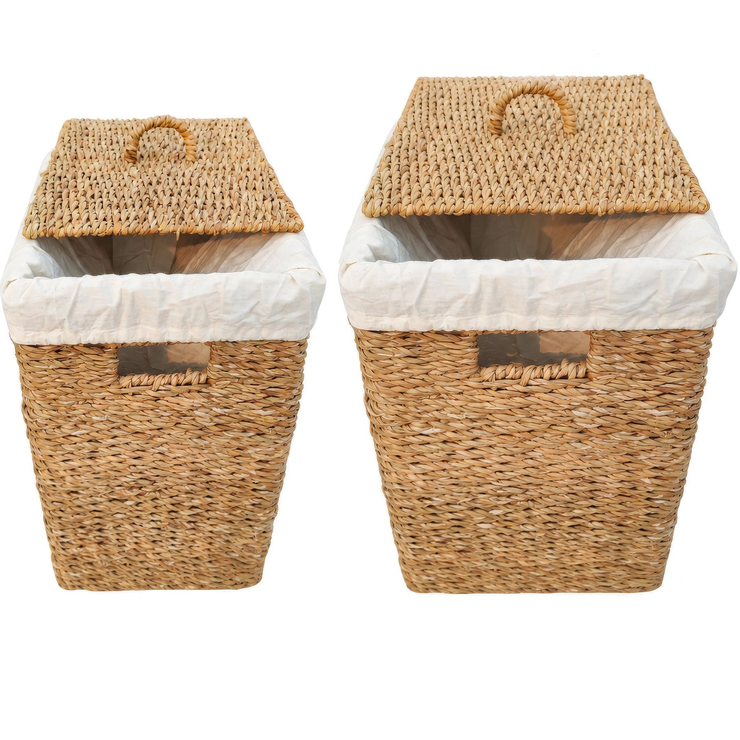 Two rectangular laundry baskets made of seagrass, with capacities of 50 and 90 liters, featuring light-colored fabric inserts and lids that rest at an angle.