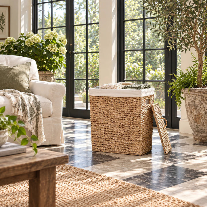 A 90-liter seagrass laundry basket with a hinged lid, filled with blankets in the sunroom.
