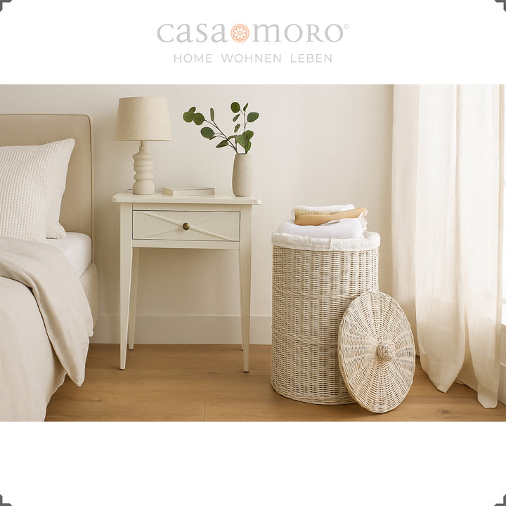 Whitewashed rattan laundry basket in the bedroom, combined with light textiles and natural light