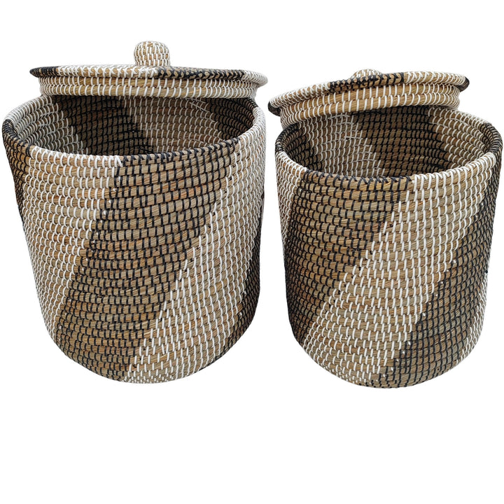 Two natural/black/white seagrass laundry baskets with raised lids and a view of the patterned interiors.