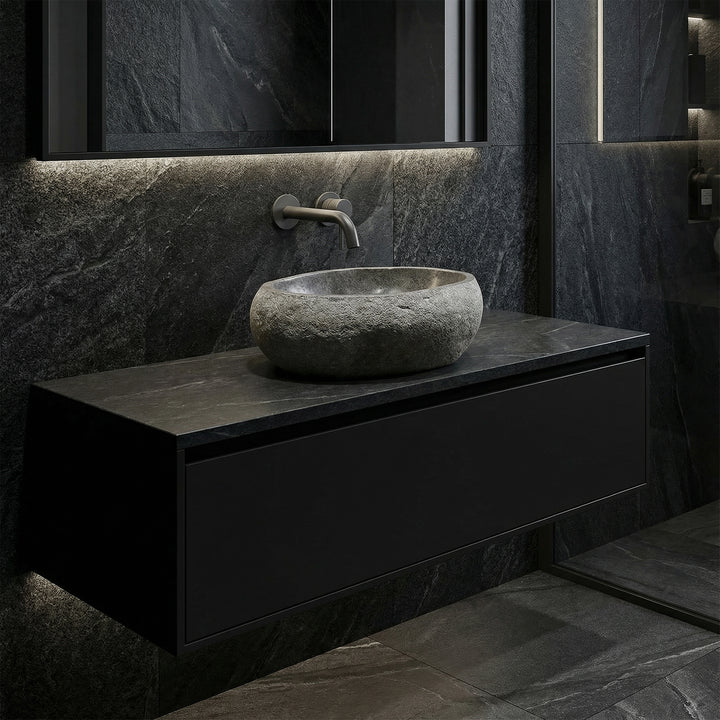 Washbasin made of dark stone in a modern bathroom on a floating base cabinet, with wall fittings and reduced lighting