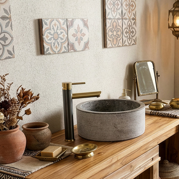 Round Washbasin made of natural stone on a warm wooden console, combined with brass fittings and oriental accents.